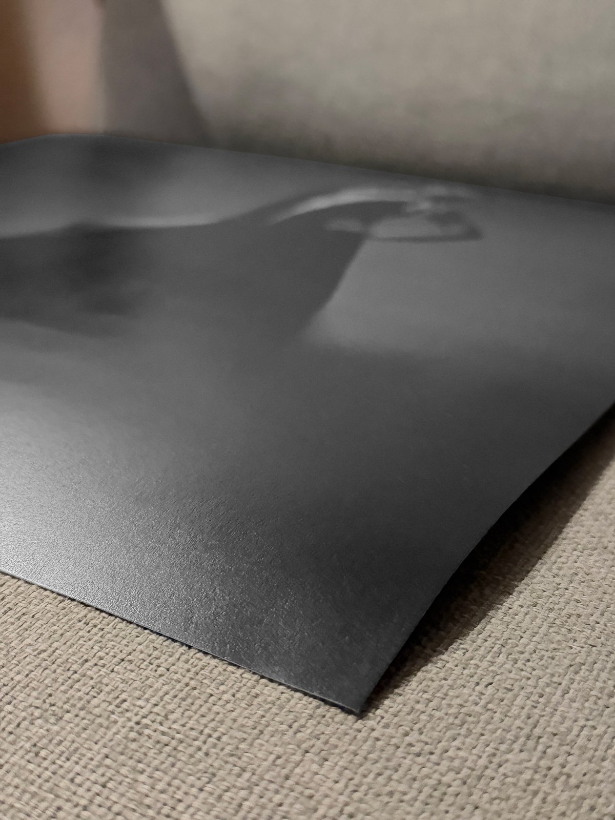Die Kante eines Fine-Art-Drucks, das Blatt woelbt sich leicht, die matte Oberflaeche ist sichtbar.